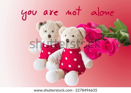 you are not alone message card handwriting with couple teddy bear and red rose arrangement flat lay postcard style on background red