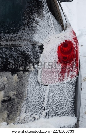 rear tail light of car covered in snow after blizzard on winter.