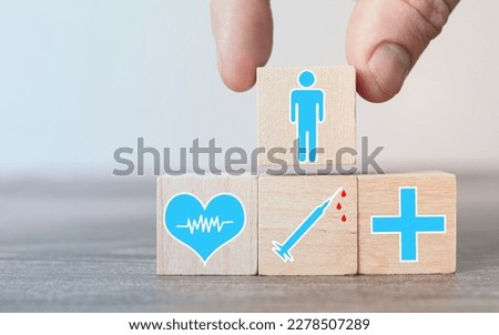 Crop person putting cube with man image on wooden blocks having picture of plus and syringe and heart with cardiogram