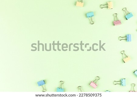 Colorful binder clips on green background, flat lay. Space for text