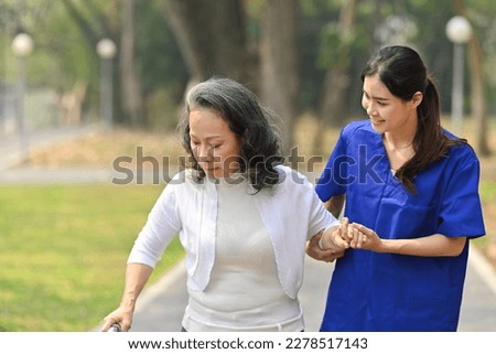 Positive female caregiver taking care of elderly woman during walking in rehabilitation center. Assistance, rehabilitation and health