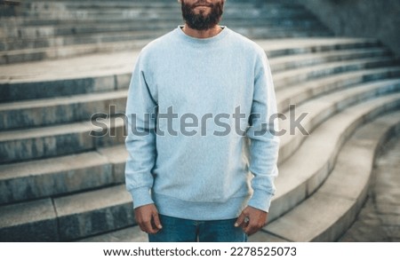 City portrait of handsome hipster guy with beard wearing gray blank sweatshirt with space for your logo or design. Mockup for print