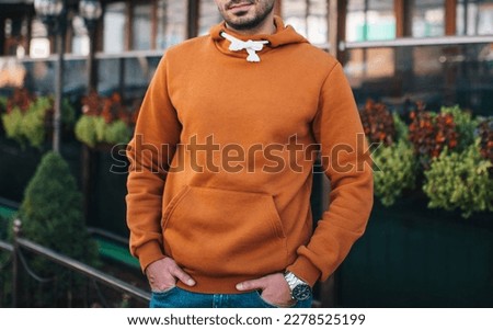 City portrait of handsome hipster guy with beard wearing brown blank hoodie or hoody with space for your logo or design. Mockup for print