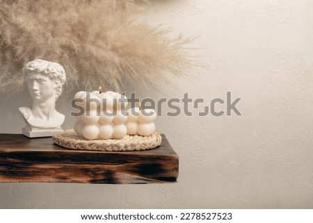 Soy wax candle on a textured table. Interior decor with a handmade burning candle. Hygge home decoration concept and aromatherapy. Bubble candle on the background of a textured wall.Place for text. Royalty-Free Stock Photo #2278527523