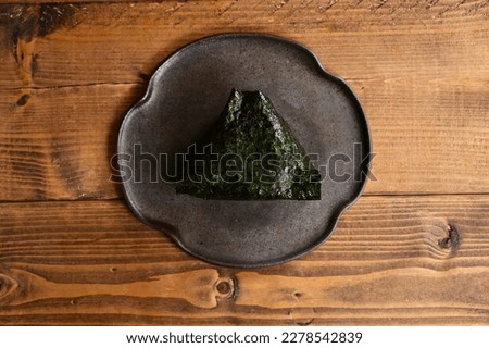 Omusubi" is a dish of rice rolled into a triangular shape and wrapped in nori (seaweed).