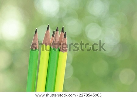 green and yellow sharp pencil on blur nature background with bokeh