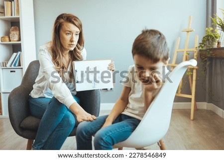 Young Boy Talking With Counselor At Home. Young female school psychologist having serious conversation with smart little boy at office. Five years old boy at the psychotherapy session.