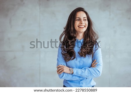 One Pretty Business Woman Standing in Hall and looking at camera with smile. Studio headshot on white background. Spanish model. Portrait of a confident young businesswoman working in a modern office