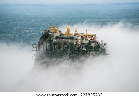 Spectacular view of Mount Popa over the clouds. Mt.Popa is the home of "Nat" the Burmese mythology ghost. This place is the old volcano in Myanmar. Royalty-Free Stock Photo #227855233