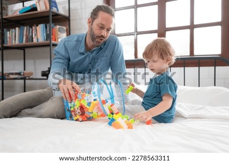 Father with little boy have fun playing with your new toys in the bedroom together. Toys that enhance children's thinking skills.