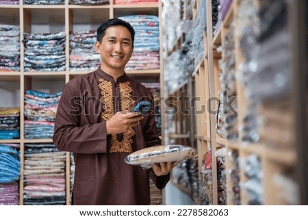 man worker checking the product of his shop while holding smartphone