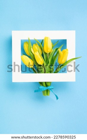 Mothers Day, International Womens Day, Valentines Day greeting card background. Holiday spring yellow tulip flowers bouquet on blue table, top view copy space.