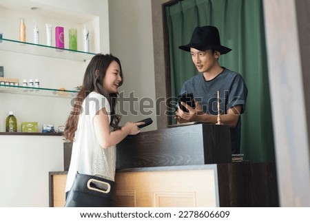 Male hairdresser and female customer paying