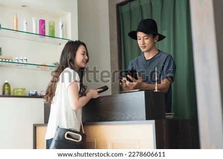 Male hairdresser and female customer paying the bill