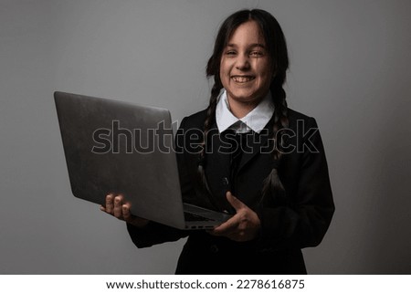 A girl with braids in a gothic style on a dark background with laptop