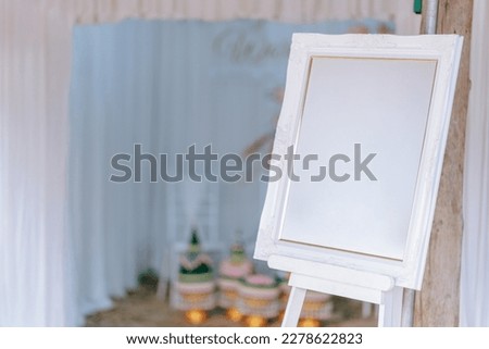 A picture frame or signboard with a blank white space is set up for wedding decorations. Clipping path.