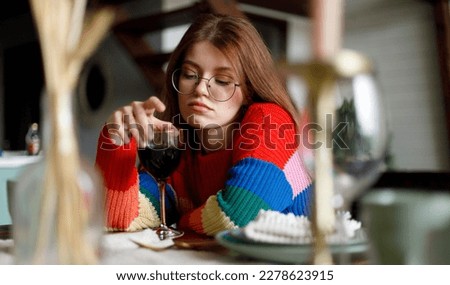 Sad young woman with a glass of wine sits at the table on a date.