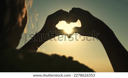heart sign. girl shows heart sign sunset with her hands. Heart hand sunset girl sun sign love. highlight happiness journey woman. hair wind light dream. picture sky relationship spring beautiful.
