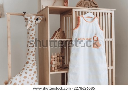 Baby sleeping bag with hanger in child room interior. Kid clothes. Copy space