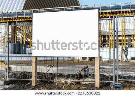 White information sign board on wooden poles on construction site at urban street outside. Housebuilding and development concept.