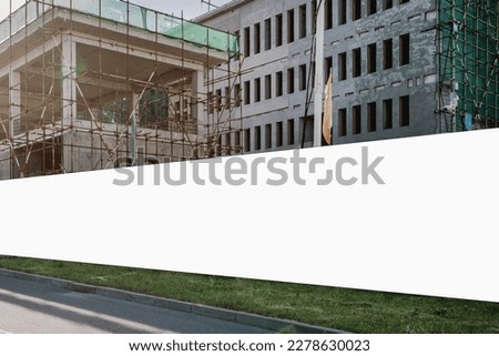 Blank hoarding with copyspace for advertising mockup on construction site with unfinished building outdoor