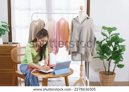 Fashion clothes online concept, Female seller measure size of dress and taking notes on notebook.