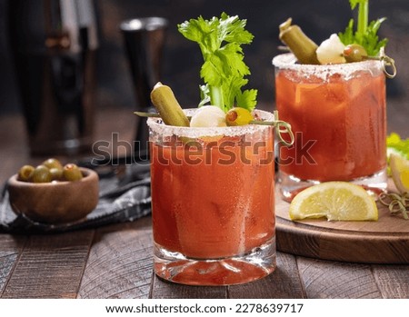 Bloody mary cocktail garnished with celery, okra, onion, olive and salt rim on a rustc wooden table Royalty-Free Stock Photo #2278639717