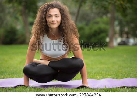 Pretty woman doing yoga exercises in outdoor park setting, nice green grass background