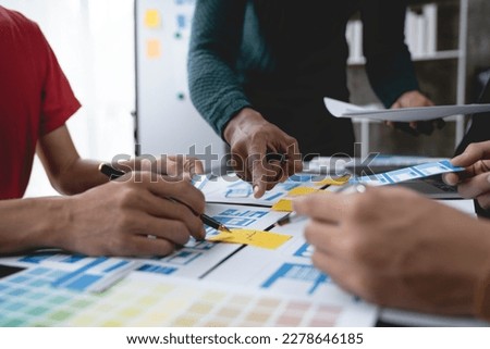 ux developers, UI designers Asian group data researchers brainstorm on tabletop mobile app interface wireframe design client summary color codes modern office Creative Digital Development Agency.