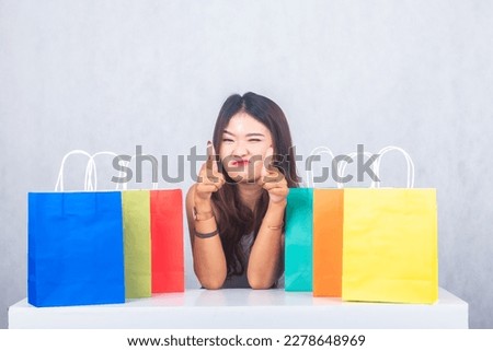 formal girl smiling sullenly shopping among colorful paper bags pointing at camera. businesswoman portrait of office career worker on white background.