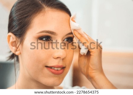 Close up woman removing make up off her face using micellar water on a cotton pad  Royalty-Free Stock Photo #2278654375