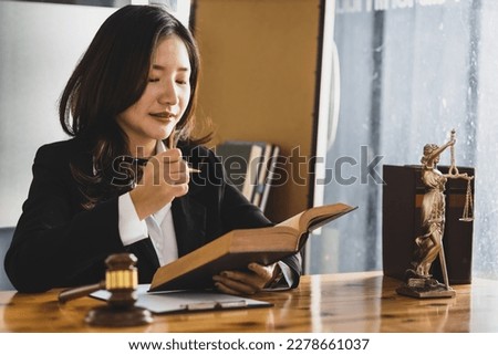 Female lawyer working in a law office reading a law book on the desk.