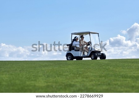 Minimal background image of sporty couple driving golf cart across field with center line horizon, copy space Royalty-Free Stock Photo #2278669929