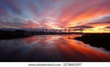 A beautiful view of the sunset with colorful sky and it's reflection in the river. The pictured was captured from a bridge.