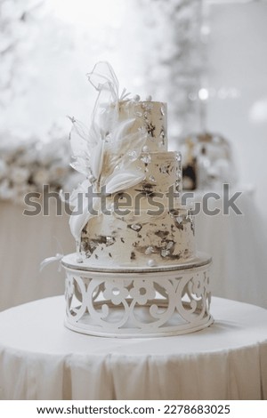 White wedding cake with flowers. Beautiful homemade three-tiered wedding cake decorated with white orchids in a rustic style on a white table