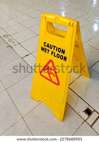 Warning signs. Seal the yellow plastic sign with Caution for Wet Floor written in the office hall after cleaning. The safety sign depicts a man sliding and slipping.

