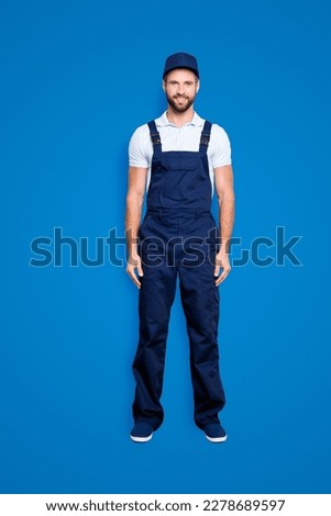 Full size fullbody portrait of attractive cheerful deliver in blue uniform with stubble looking at camera holding, isolated on grey background Royalty-Free Stock Photo #2278689597