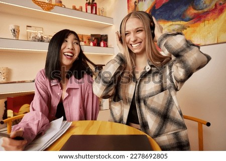 Girlfriends dancing and listen music from a laptop computer at home. Girls having fun at apartment.