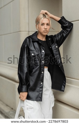blonde woman in leather shirt jacket posing with handbag on street in Miami