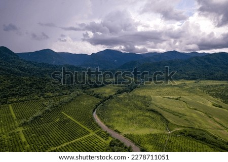 Aerial photo of a winding river through a valley along the Hummingbird Highway with rain clouds.