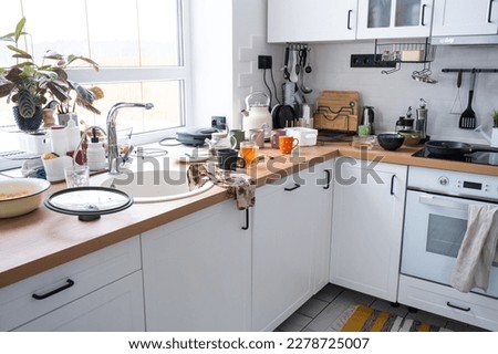 A mess in the kitchen, dirty dishes on the table, scattered things, unsanitary conditions. The dishwasher is full, the kitchen is untidy, everyday life Royalty-Free Stock Photo #2278725007