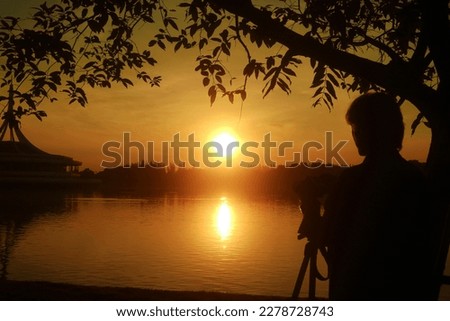 Silhouette of a person watching and photographing the beautiful sunrise