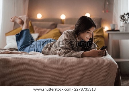 Young teenage girl srolling her smartphone in the room. Royalty-Free Stock Photo #2278735313