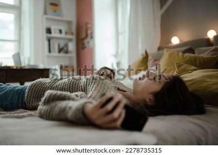 Young teenage girl with smartphone in the room. Royalty-Free Stock Photo #2278735315