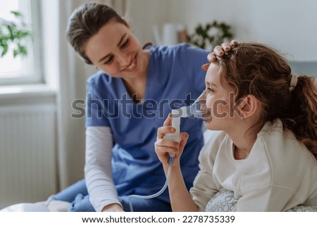 Little girl with inhaler in hospital room, nurse chcecking her. Royalty-Free Stock Photo #2278735339