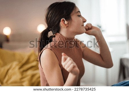 Teenage girl with hearing aid listening music in her room. Royalty-Free Stock Photo #2278735425