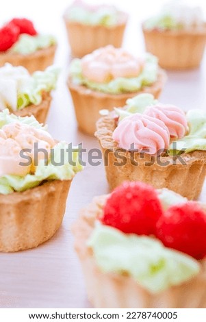 Group of cupcakes decorated with frosting and raspberries.