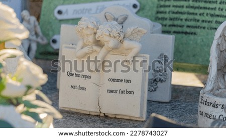 
Funerary plaque in the shape of a book, surmounted by two angels, with the inscription: "May your rest be sweet as your heart was good" Royalty-Free Stock Photo #2278743027