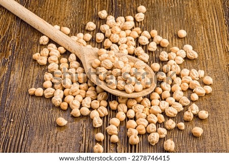 a pile of chickpeas and on top of the pile a wooden spoon with chickpeas