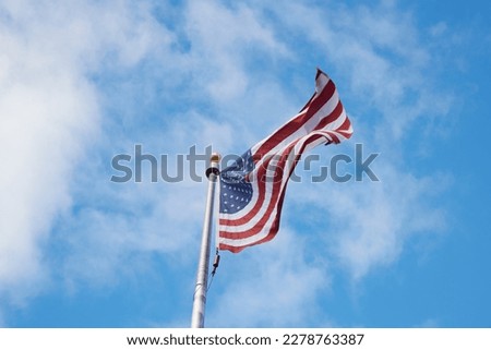American Flag Blowing in the Wind on a Bright Blue Sky with Clouds Royalty-Free Stock Photo #2278763387